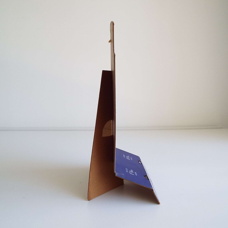 以下が含まれることがあります： 青と白のデザインの段ボール製スタンド。スタンドは三角形に折り畳まれており、看板用のスロットがあります。