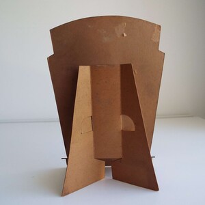 以下が含まれることがあります： 茶色の長方形の背面パネルと三角形のベースを持つ段ボール製のスタンド。スタンドはポスターやディスプレイを保持するために設計されています。