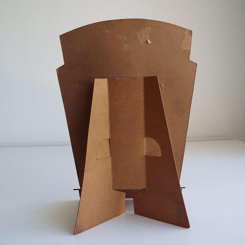 以下が含まれることがあります： 茶色の長方形の背面パネルと三角形のベースを持つ段ボール製のスタンド。スタンドはポスターやディスプレイを保持するために設計されています。