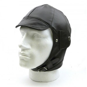 May include: A brown leather aviator hat with ear flaps and a buckle strap. The hat has a short brim and a pointed crown.