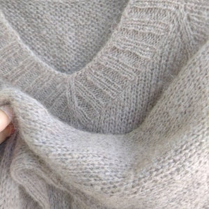 Pu&ograve; includere: Un maglione di lana morbido di colore marrone chiaro con scollo a V.