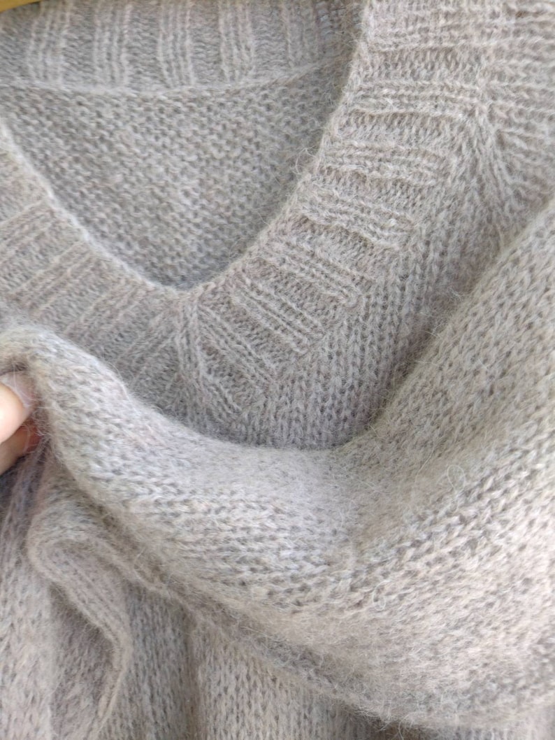 Pu&ograve; includere: Un maglione di lana morbido di colore marrone chiaro con scollo a V.