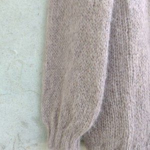 Pu&ograve; includere: Un maglione di lana morbido, di colore marrone chiaro, con una texture soffice.