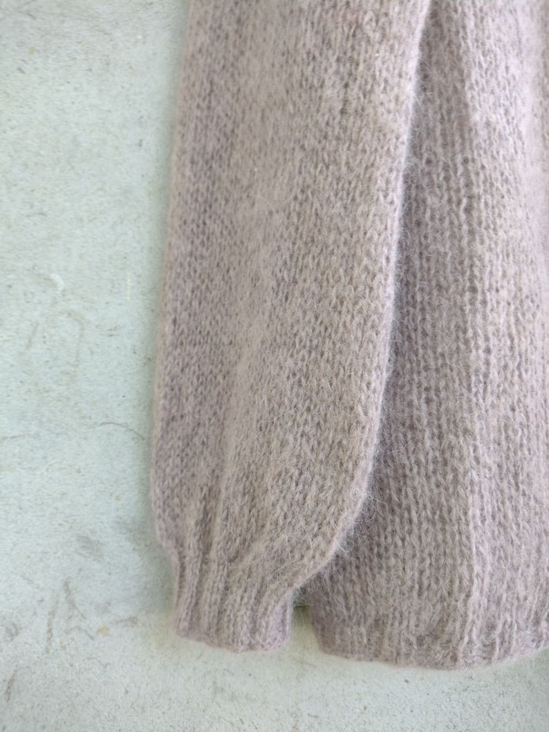 Pu&ograve; includere: Un maglione di lana morbido, di colore marrone chiaro, con una texture soffice.