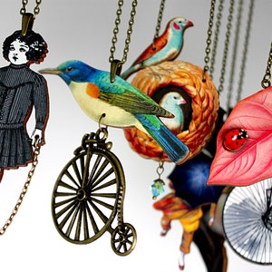 May include: A collection of necklaces with various charms, including a girl in a black dress, a blue bird, a bird's nest, a leaf with a ladybug, and a bicycle. The necklaces are made of metal chains and have a vintage aesthetic.