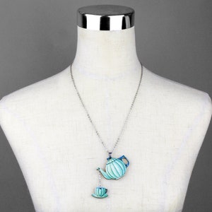 May include: A silver chain necklace with a blue and green teapot and a matching teacup pendant.