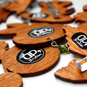 May include: A set of wooden pins with a circular design featuring the text "DP, Berlin". The pins are in various shapes and sizes, and some have a silver pin back.