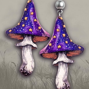 May include: A pair of purple and gold mushroom earrings with a starry sky design. The earrings are made of polymer clay and have a silver hook.