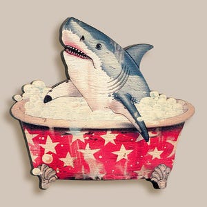 May include: A white shark with a gray back is taking a bath in a red and white bathtub with stars. The bathtub has white foam around the edges.