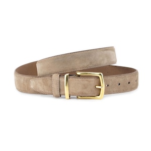 May include: A tan suede belt with a gold-coloured buckle. The belt is a neutral colour and has a classic design. The buckle is rectangular and has a shiny finish. The belt is suitable for casual or formal wear.