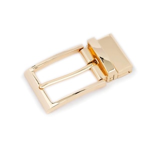May include: A gold-toned metal belt buckle with a rectangular shape and a smooth finish.