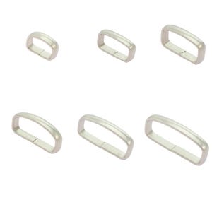 May include: Six silver-toned metal rectangular rings. The rings have a smooth, matte finish and a slightly curved top. They are arranged in two rows of three against a white background. These rings are likely used for crafting or hardware.