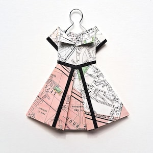 May include: A white ceramic mug with a black handle and the text "But First, Coffee" in a bold, black font. The mug is set against a blurred background, suggesting a cozy setting.