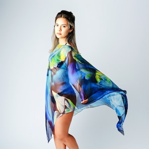 May include: A woman wearing a blue, green, and purple patterned sheer dress with a flowing design. The dress is loose fitting and has a flowing skirt.