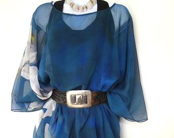 May include: A teal blue sheer top with a white floral print and a black belt. The top is made of a lightweight fabric and has a loose, flowing fit.