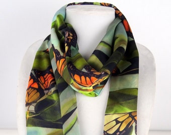 May include: A green, blue, and black silk scarf with a repeating pattern of orange and black butterflies on a leafy background.