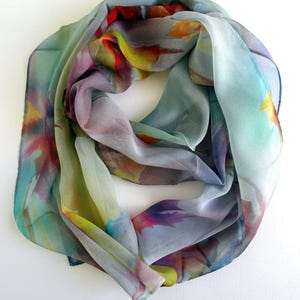 May include: A light blue silk scarf with a watercolor print of colorful flowers and leaves.