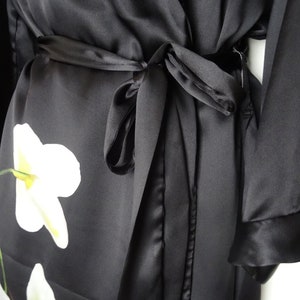 May include: Black satin robe with a white floral print and a matching tie belt.