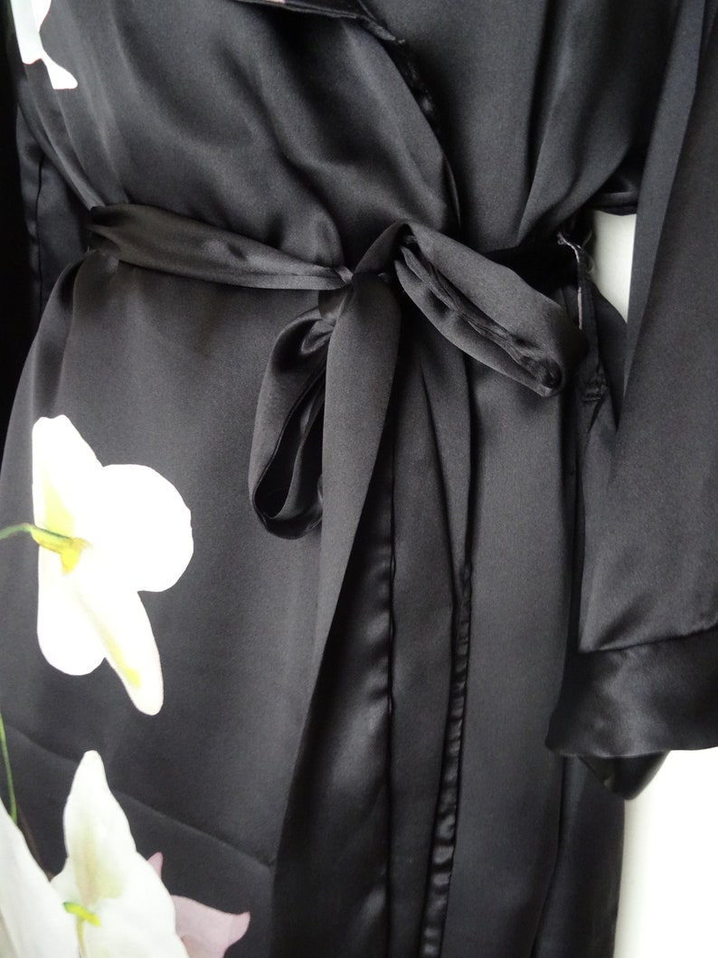 May include: Black satin robe with a white floral print and a matching tie belt.