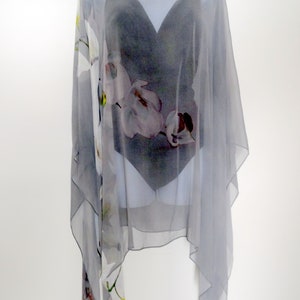May include: A gray sheer poncho with a floral print. The poncho has a scoop neck and a loose fit.