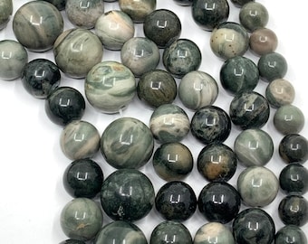 May include: Strands of round, polished beads in shades of green, gray, and brown. The beads have a marbled appearance, with variations in color and pattern. The beads are strung together, ready for jewelry making or other crafts.