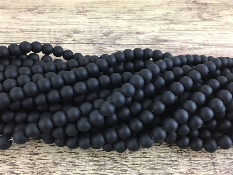May include: A strand of black matte round beads. The beads are smooth and have a slightly textured surface.