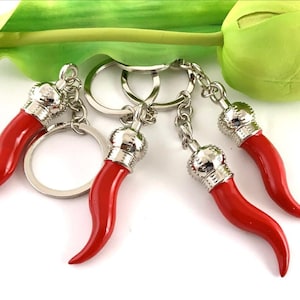 May include: A set of four red pepper keychain charms with silver metal rings and a silver metal chain. The charms are shaped like Italian horn peppers.