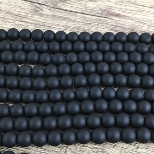 May include: A strand of black matte round beads. The beads are smooth and have a slightly textured surface.