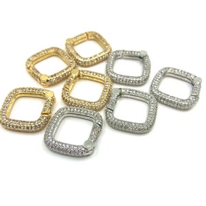 May include: A group of seven square-shaped clasps with a hinged opening. The clasps are made of metal and are adorned with clear rhinestones. Some clasps are gold-toned and others are silver-toned.