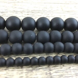 May include: A set of black matte beads in various sizes. The beads are arranged in rows, with the largest beads at the top and the smallest beads at the bottom.