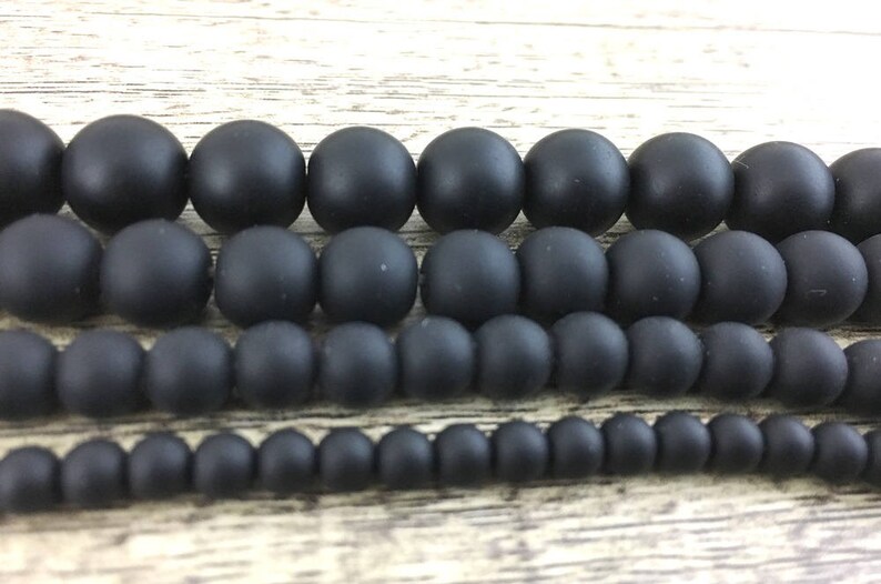 May include: A set of black matte beads in various sizes. The beads are arranged in rows, with the largest beads at the top and the smallest beads at the bottom.