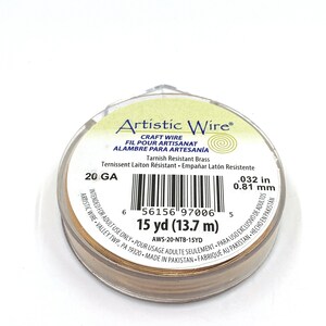 May include: A spool of Artistic Wire craft wire in a clear plastic container. The wire is a tarnished brass color, 0.032 inches in diameter, and 15 yards (13.7 m) long. The label includes the text "Artistic Wire".