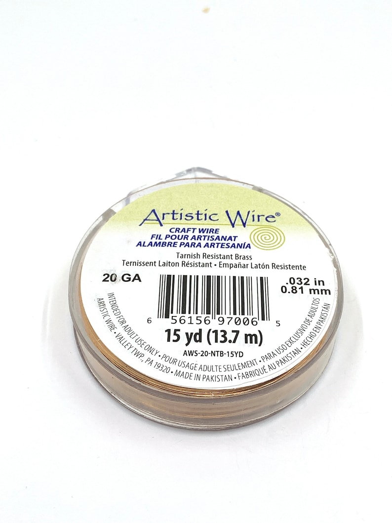 May include: A spool of Artistic Wire craft wire in a clear plastic container. The wire is a tarnished brass color, 0.032 inches in diameter, and 15 yards (13.7 m) long. The label includes the text "Artistic Wire".