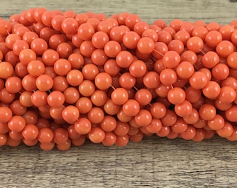 May include: A large collection of smooth, round, vibrant orange beads strung together on thin clear filaments. The beads have a glossy finish and are uniform in size, creating a dense, textured cluster of bright, solid-colored spherical elements.