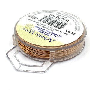 May include: A spool of Artistic Wire craft wire in a warm brass color. The label indicates 15 yards (13.7 m) of 20 gauge wire, with a tarnish-resistant finish. The spool is held in a clear plastic holder.