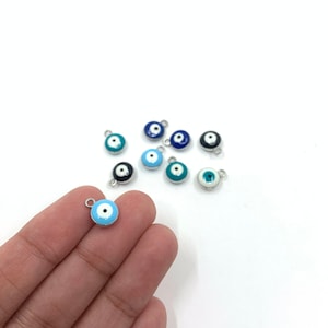Evil eye charms shown on hand for size reference.