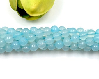 May include: A strand of light blue round gemstone beads. The beads are smooth and polished.