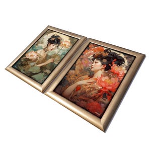 May include: Two framed paintings of women in traditional Asian clothing. The woman in the left painting is holding a lotus flower and is surrounded by green foliage. The woman in the right painting is wearing a red and gold robe and is surrounded by pink flowers.