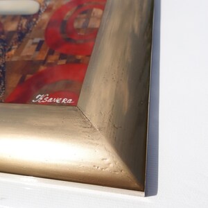 a close-up view of a gold-colored frame with a red and black abstract design on the inside.