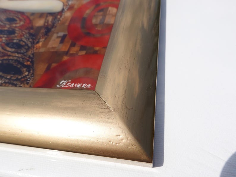 a close-up view of a gold-colored frame with a red and black abstract design on the inside.