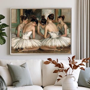 The image is a framed painting depicting a group of ballet dancers in white tutus and green ballet slippers, arranged in a semi-circle on a stage.
