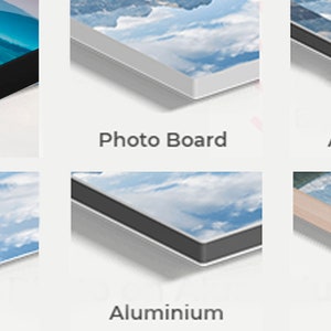 May include: Close-up of six different types of canvas prints, including canvas, photo board, acrylic+alu, acrylic, aluminum, and wood. Each print features a blue sky with white clouds.