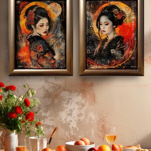 May include: Two framed art prints depicting portraits of women in traditional Japanese dress. The artwork has a dark background with a circular orange and yellow glow behind the subjects. The women have dark hair and wear black kimonos.