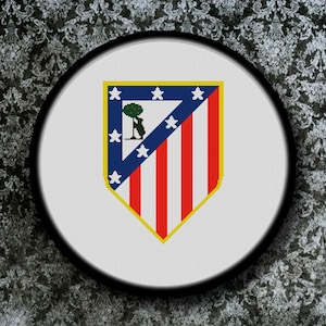 May include: A white and red shield with a yellow border and a small green tree in the upper left corner. The shield has seven red stripes and seven white stars around the border.