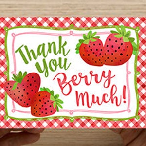 May include: Thank you berry much! Greeting card with a red and white gingham background and a white frame with the text "Thank you berry much!" and illustrations of red strawberries.