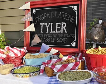 Puede incluir: Un letrero de pizarra roja con letras blancas que dice "Congratulations Tyler Always Swing for the Fences Class of 2015". El letrero está rodeado de banderas de banderines rojas, blancas y azules. Hay varios alimentos en una mesa cubierta con un mantel a cuadros azules y blancos.