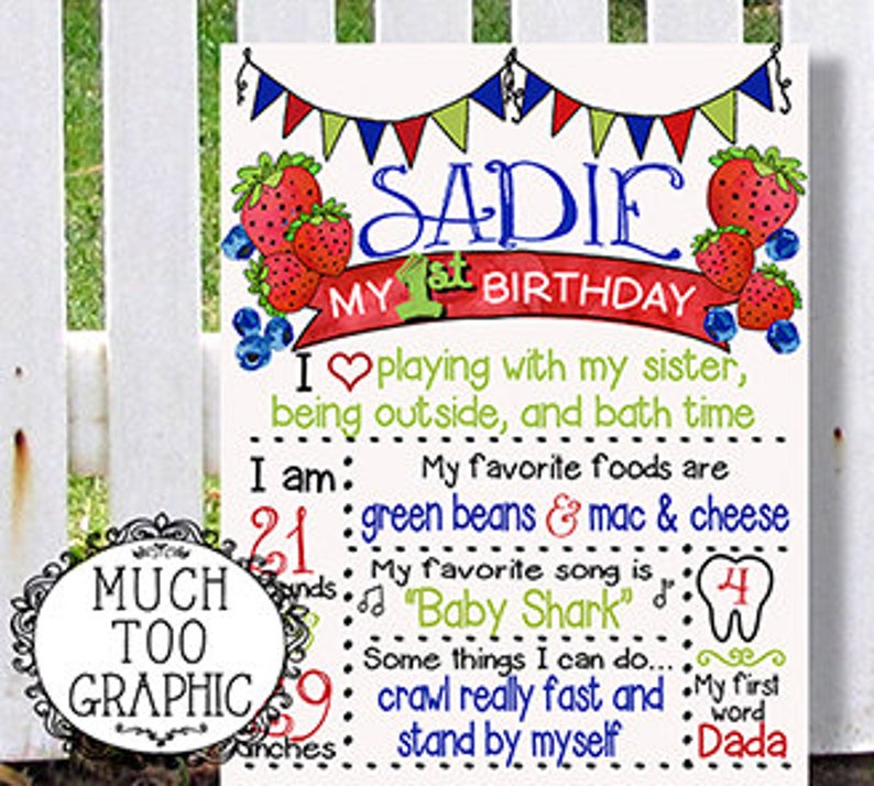 May include: A colorful printable first birthday sign for a girl named Sadie. The sign features a strawberry theme with red, blue, and green colors. It includes details about Sadie's age, favorite foods, songs, and activities. The text reads: "Sadie My 1st Birthday I  playing with my sister, being outside, and bath time I am: 21 months My favorite foods are green beans & mac & cheese My favorite song is "Baby Shark" Some things I can do... crawl really fast and stand by myself My first word Dada"