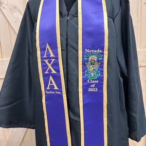 May include: Purple and gold graduation stole with the Greek letters Delta Chi Alpha, Epsilon Iota, and the words "Nevada" and "Class of 2022".