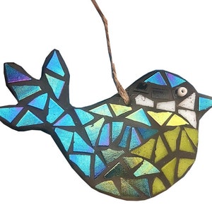 May include: A mosaic bird ornament with iridescent blue, green, and yellow glass pieces. The bird has a dark gray outline and a small white bead for an eye. A brown string is attached for hanging.