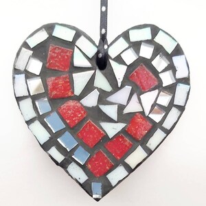 May include: A red, white, and silver mosaic heart ornament with a black ribbon for hanging.